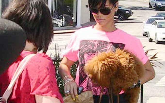 Dainininkė Rihanna geltoną nagų laką derina prie neoninės spalvos marškinėlių.